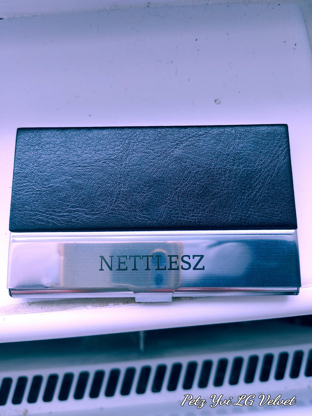 Közelkép a gravírozott NETTLESZ fém névjegytartóról